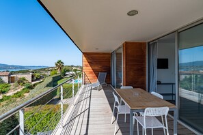 A balcony with a wooden table and chairs, a pool, and a view of the landscape. - Via Mare - Apt avec splendide vue (Grosseto-Prugna)