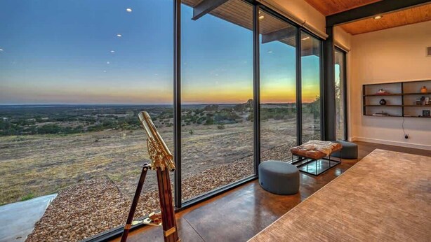 Un interior moderno con ventanas amplias que ofrecen vistas a un paisaje.