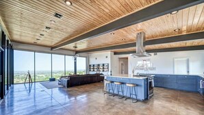 Una cocina amplia con una isla grande, taburetes de bar y vistas del paisaje a través de ventanas panorámicas.