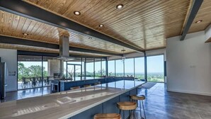 Cocina moderna con una isla grande, taburetes de bar y vistas al exterior.
