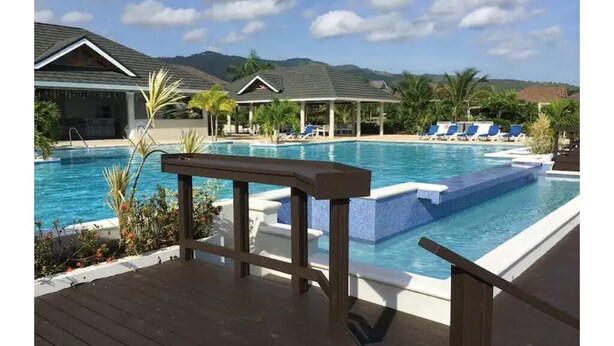 A pool area with lounge chairs and a wooden deck. - Cozy 3-Bedroom Vacation Home (Richmond Estates)