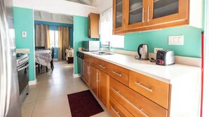 A compact kitchen with wooden cabinets, a white countertop, and basic appliances. - Cozy 3-Bedroom Vacation Home (Richmond Estates)