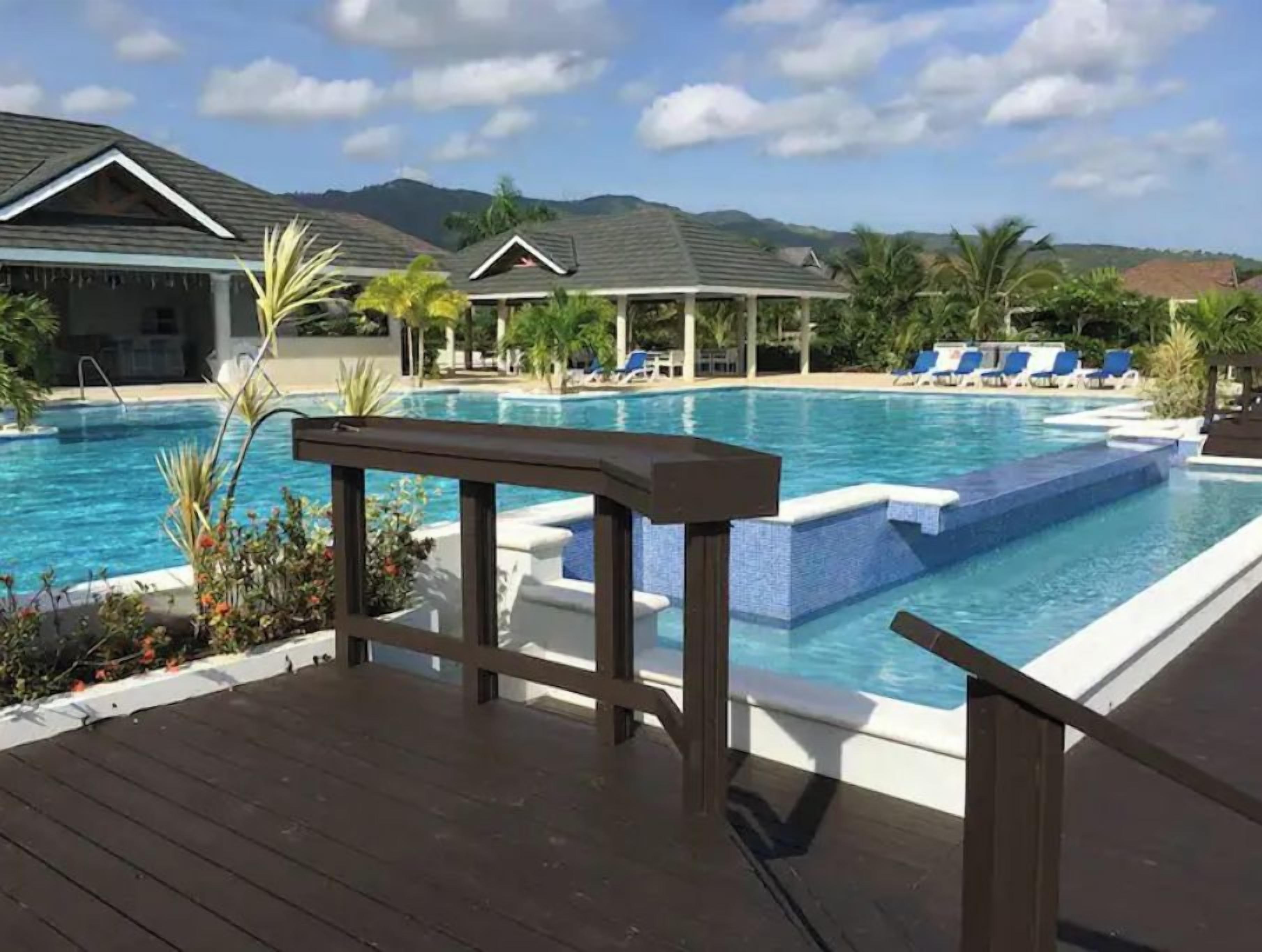 Un área de piscina con sillas de descanso y una terraza de madera.