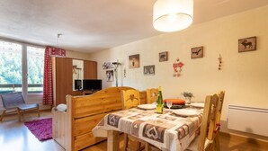 Une pièce confortable avec une table à manger en bois, un lit et un téléviseur.