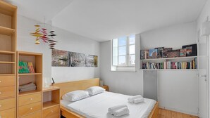A modern bedroom with a wooden bed, a bookshelf, and a window.