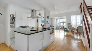 A modern kitchen with a central island, wooden flooring, and a view to a dining area with chairs and a table.