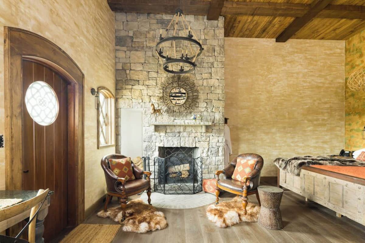 A cozy living room with a stone fireplace, leather armchairs, and a wooden table.
