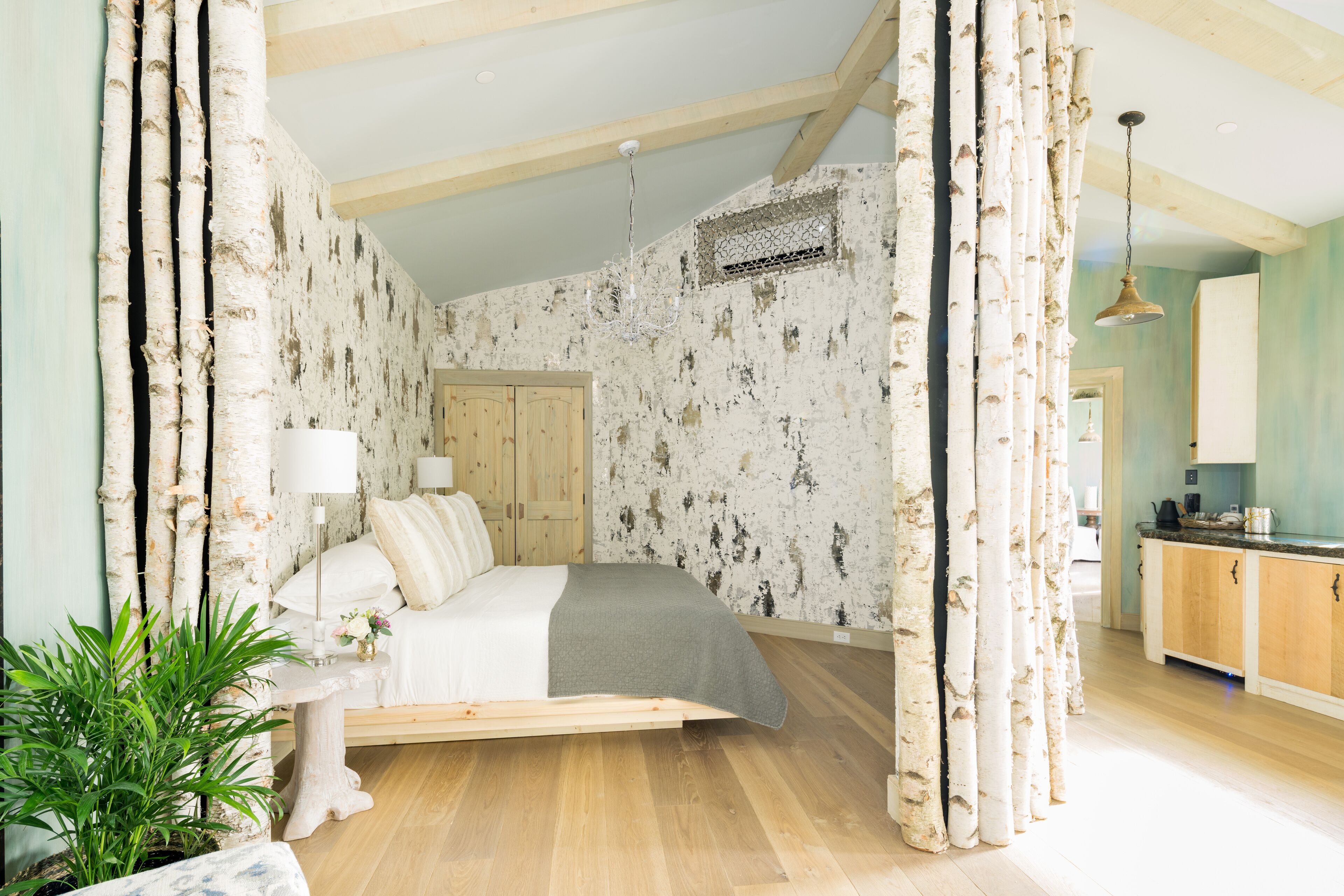 Un dormitorio con cama de madera, una mesita de noche y un ventanal grande.
