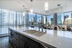 A modern kitchen with a large island, stainless steel appliances, and a city view through floor-to-ceiling windows. - 2 Story luxury penthouse in downtown Calgary (Calgary)