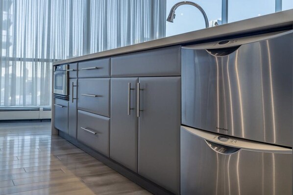 A modern kitchen with stainless steel appliances, a large window, and a wooden floor. - 2 Story luxury penthouse in downtown Calgary (Calgary)