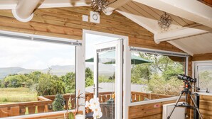 A wooden deck with a table, a telescope, and a view of the outdoors. - Ty Coed - 63 (Blaenau Ffestiniog)