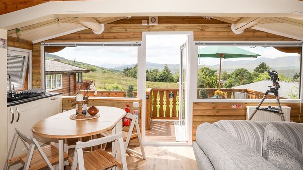 A cozy cabin interior with a dining area, kitchen, and a balcony with a telescope. - Ty Coed - 63 (Blaenau Ffestiniog)
