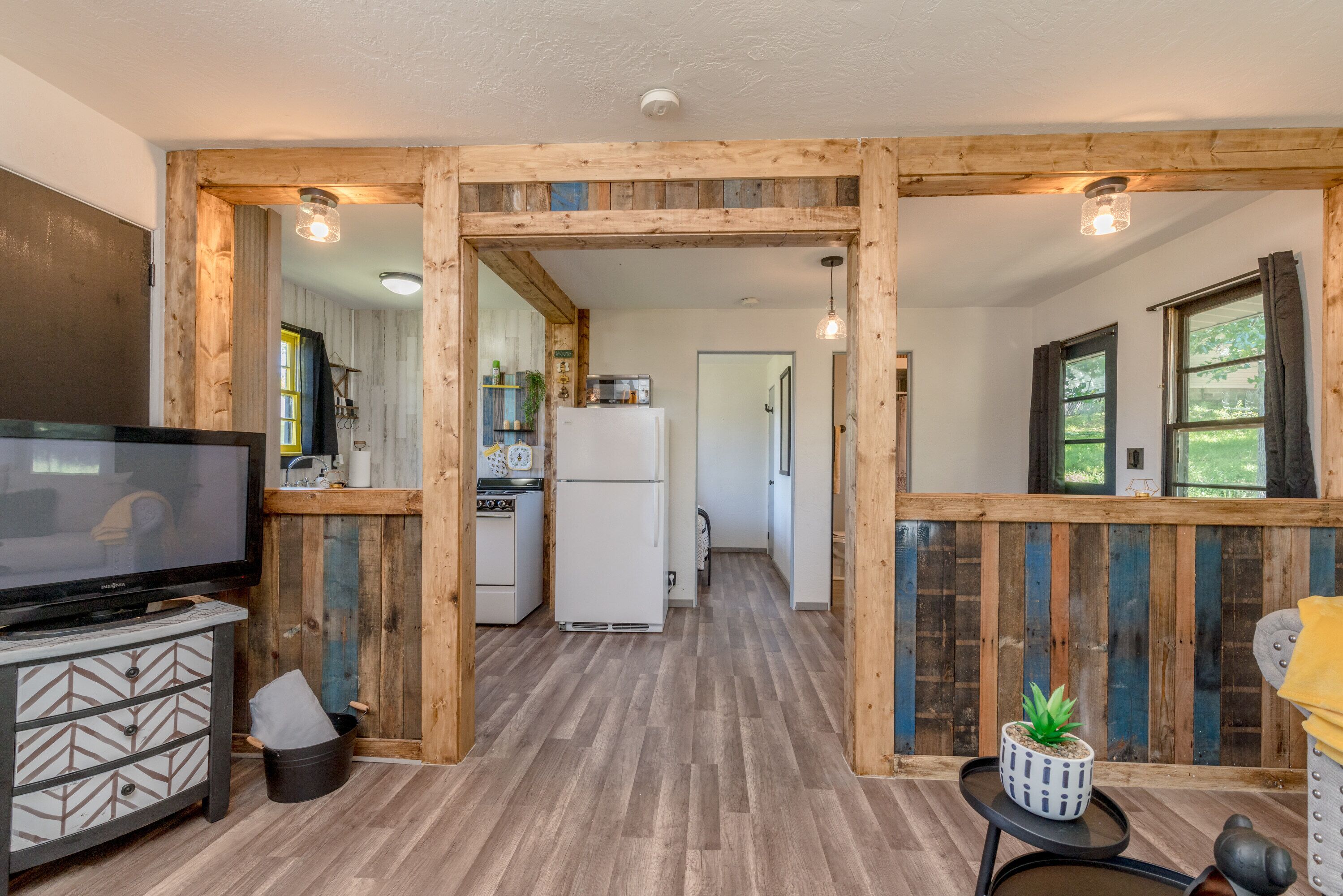 A modern kitchen with wooden accents, a TV, and a small dining area.