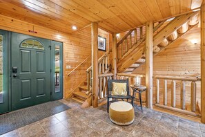 A wooden interior with a green door, a staircase, and a chair with a cushion. - Luxury 6-Bedroom Lodge Dubuque, Field of Dreams & Galena (Durango)