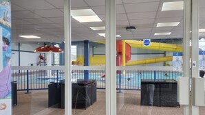 A pool area with a glass door entrance, tiled flooring, and a ceiling with fluorescent lights. - 3 Bedroom Static Caravan, Hoburne Devon Bay (Paignton)