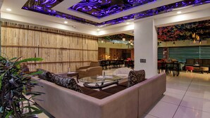 A modern living room with a glass coffee table, sofas, and a bamboo wall. - Treebo Nearmi Bell House (Gurugram)