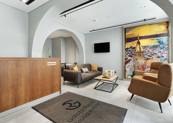 A modern hotel lobby with a reception desk, seating area, and a large painting of a cityscape. - Galata Rasso Boutique Hotel (Istanbul)