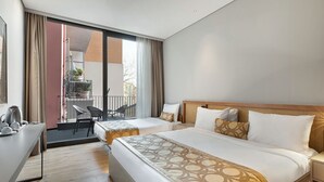 A hotel room with two beds, a desk, and a balcony with chairs and a potted plant. - Galata Rasso Boutique Hotel (Istanbul)