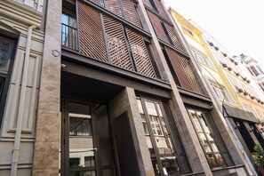 A multi-story building with large windows, a balcony with a lattice design, and a visible door. - Galata Rasso Boutique Hotel (Istanbul)