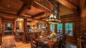 A log cabin interior with a dining area, wooden furniture, and large windows. - Luxury Log Cabin Home at Bass Lake with Air Conditioning, with backup generator  (Bass Lake)