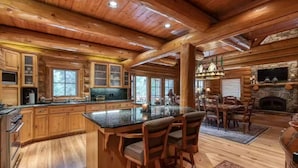 A log cabin interior with a large kitchen, dining area, and fireplace. - Luxury Log Cabin Home at Bass Lake with Air Conditioning, with backup generator  (Bass Lake)