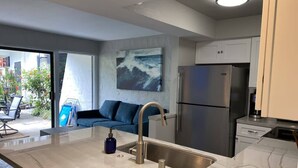 A modern kitchen with a large island, stainless steel appliances, and a blue sofa in the adjacent living area.