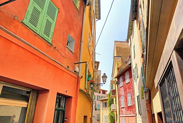 Une rue étroite, bordée de bâtiments des deux côtés, avec des balcons et des fenêtres.