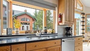 A kitchen with wooden cabinets, a stainless steel sink, and a coffee maker. - Chateau Lawrence | Pool Table | Kids` Gaming Room (Fairmont Hot Springs)