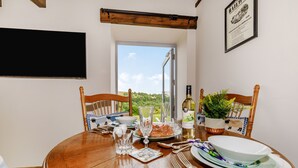 A dining table set with plates, glasses, and cutlery, with a window view of greenery. - Foxglove (Whitby)