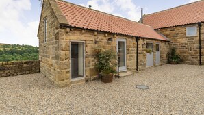 A stone building with a red-tiled roof, a gravel driveway, and potted plants. - Foxglove (Whitby)