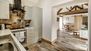 A modern kitchen with white cabinets, a built-in oven, and a stone backsplash. - Foxglove (Whitby)