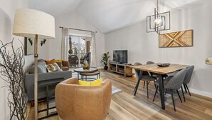 A modern living room with a sofa, a coffee table, and a dining area with chairs and a table. - High Noon | Top Floor | Pool | Hot Tub | Gym (Invermere)