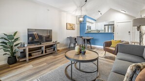 A modern living room with a TV, dining area, and kitchen. - High Noon | Top Floor | Pool | Hot Tub | Gym (Invermere)