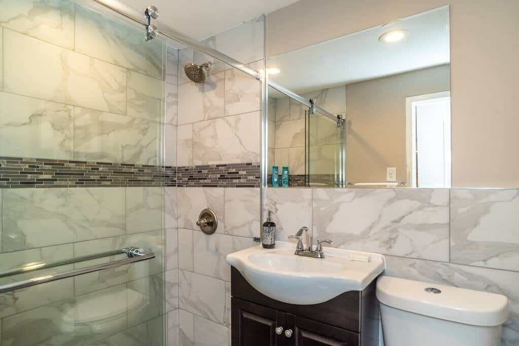 A bathroom with a glass shower enclosure, a white sink, and a toilet.