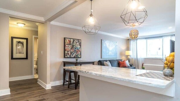 A modern kitchen with a marble countertop, pendant lighting, and a dining area with a table and chairs. - Upgraded Atlanta Apartment with Pool (Atlanta)