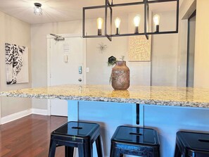 Enjoy cooking in this well-equipped kitchen with a granite countertop, stainless steel backsplash, and modern lighting.