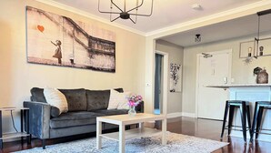 Un salon moderne avec un canapé gris, une table basse blanche et un tapis à motifs.