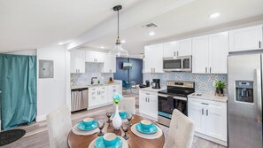 A modern kitchen with white cabinets, a stainless steel refrigerator, a microwave, and a stove. - Spacious pet-friendly 3BR home with fast Wi-Fi, full kitchen, free parking, and on-site laundry. (Orlando)