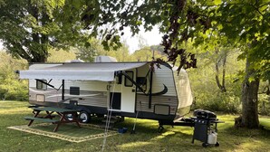 Un véhicule récréatif (VR) est stationné sur une pelouse, à proximité d’une table de pique-nique et d’un barbecue.