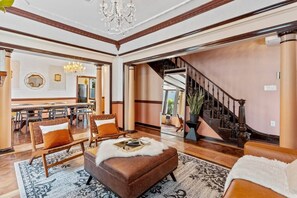 Un vaste salon doté d’une cheminée, d’un coin repas et d’un escalier menant à l’étage supérieur.
