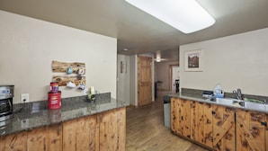 A kitchen with wooden cabinets, granite countertops, a coffee maker, and a coffee pot. - Birch Glen Lodge (Cascade)
