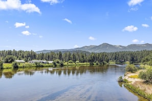 A calm river with a forested mountain range in the background.