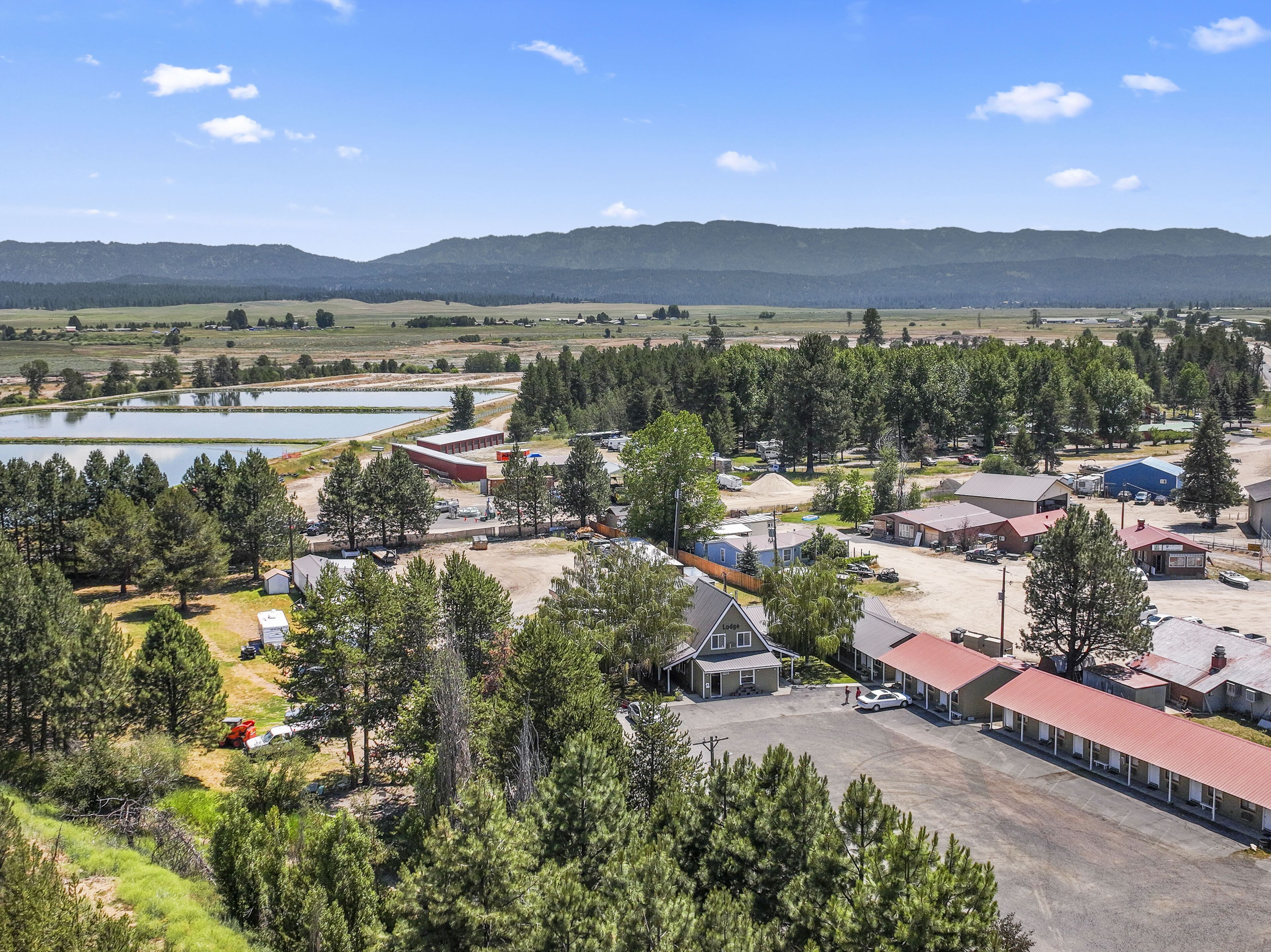 A rural area with a mix of residential and commercial buildings, a large open parking area, and a body of water in the background.
