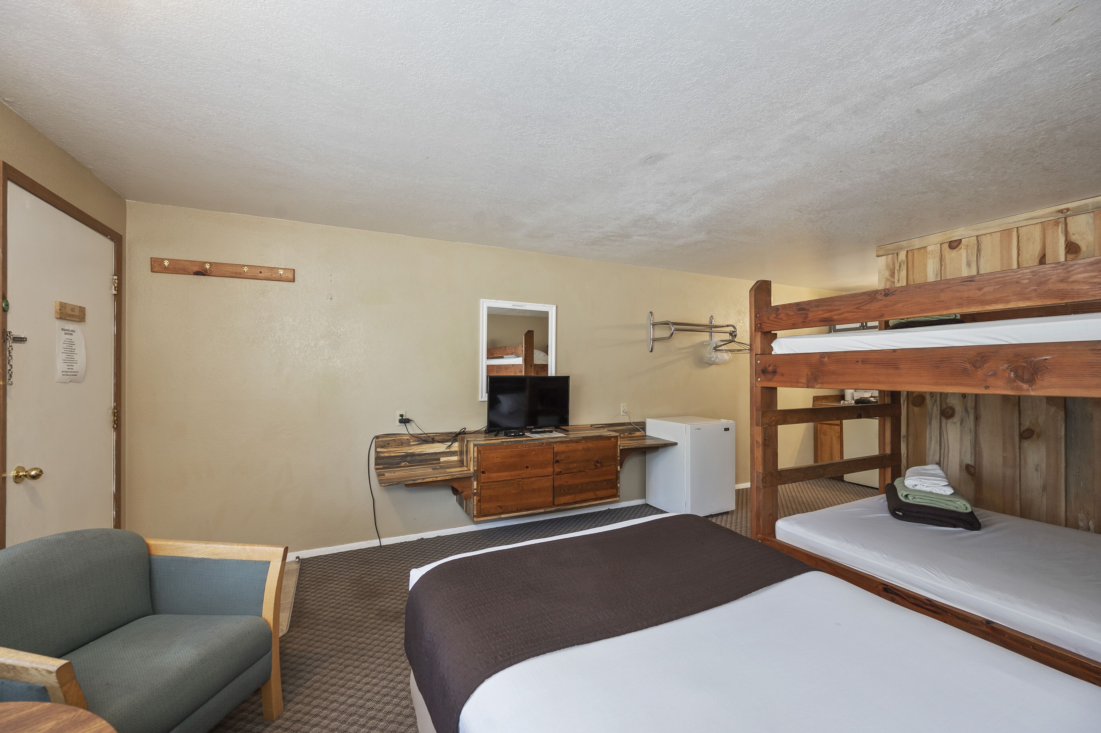 A room with bunk beds, a desk with a television, and a chair.