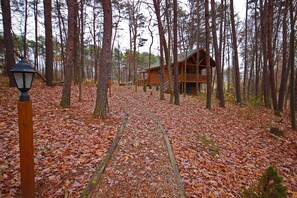 A wooden cabin in a forest with a path leading to it. - Whispering Pines - Cozy, Log Cabin - Hocking Hills (Logan)