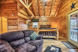 A log cabin interior with a sofa, a bunk bed, and a wooden ceiling.