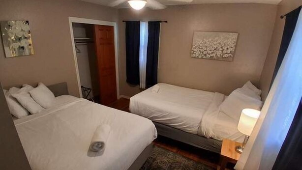 A hotel room with two beds, a ceiling fan, a rug, and a painting on the wall. - Near Midtown, Highways, Downtown! Bel-Air Bungalow (Mobile)