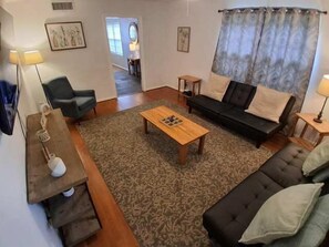 A living room with a sofa, a coffee table, and a television. - Near Midtown, Highways, Downtown! Bel-Air Bungalow (Mobile)