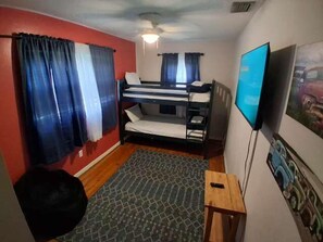 A room with bunk beds, a television, and a patterned rug.