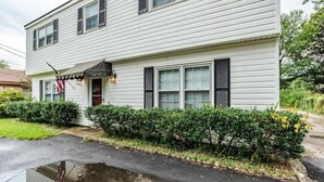 A two-story house with a front porch, a small garden, and a visible driveway. - Near Midtown, Highways, Downtown! Bel-Air Bungalow (Mobile)